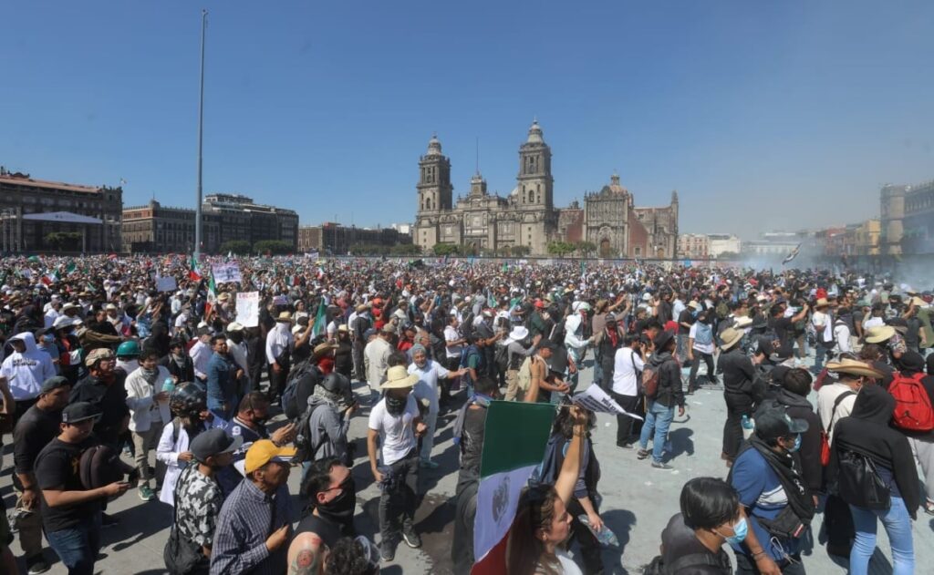 Manifestantes marchando por calles del Centro Histórico de la Ciudad de México con pancartas