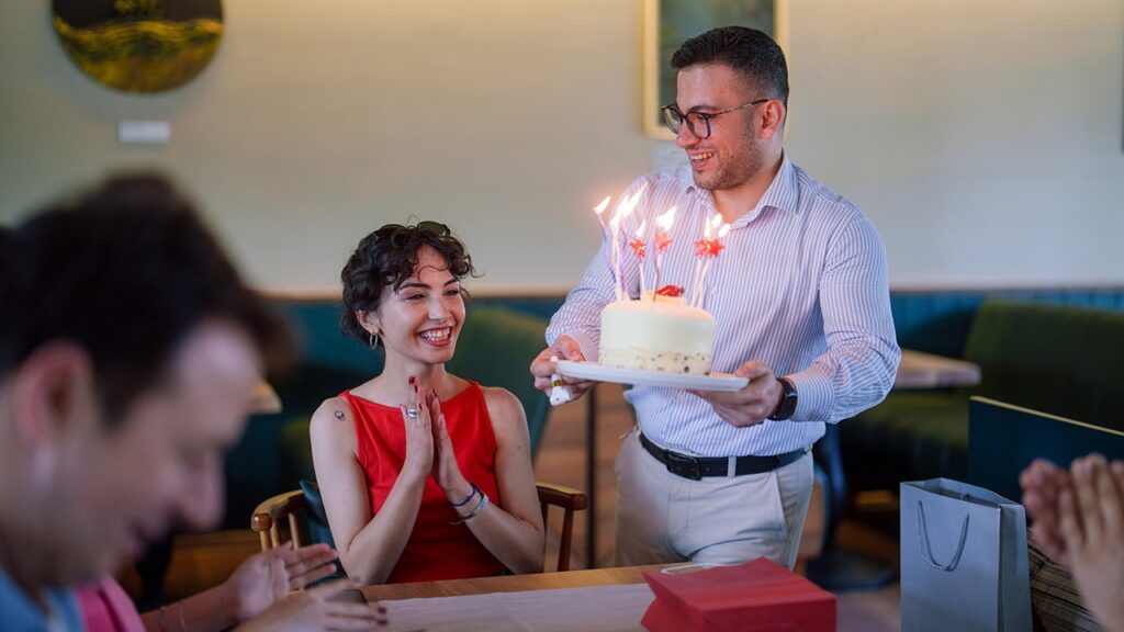 Pastel de cumpleaños con velas encendidas sobre mesa de restaurante